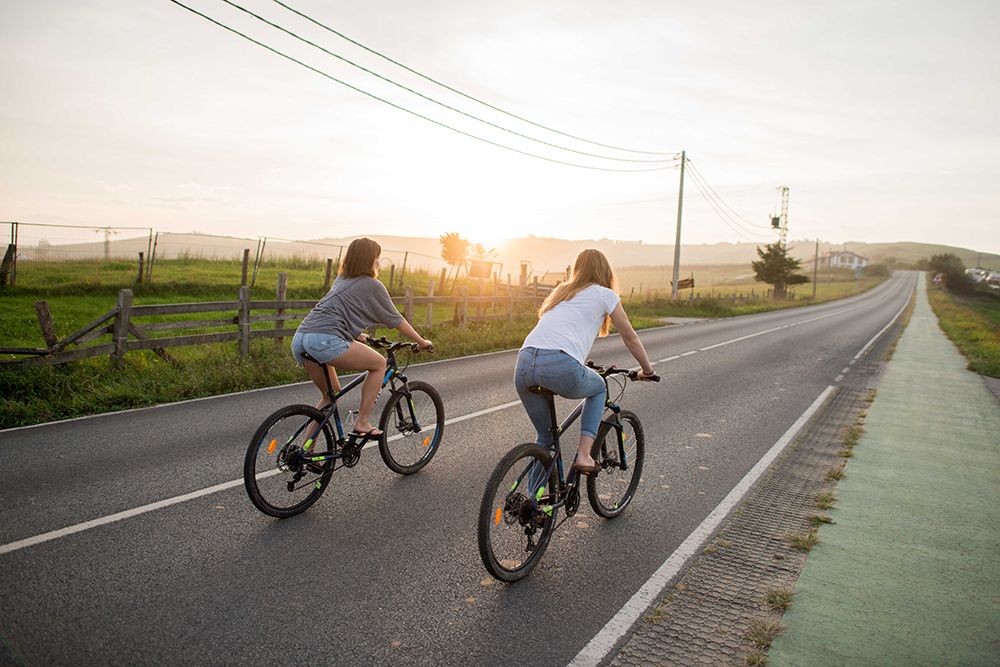 chicas en bicicleta en la playa de oyambre